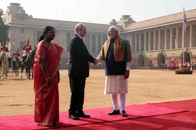 In this pool photograph distributed by the Russian state agency Sputnik, Russia's President Vladimir Putin shakes hands with India's Prime Minister Narendra Modi as Indian President Droupadi Murmu stands nearby during the Russian leader's ceremonial reception at India's presidential palace, Rashtrapati Bhavan, in New Delhi on December 5, 2025. (Photo by Konstantin ZAVRAZHIN / POOL / AFP) / ***Editor's note : this image is distributed by the Russian state owned agency Sputnik***