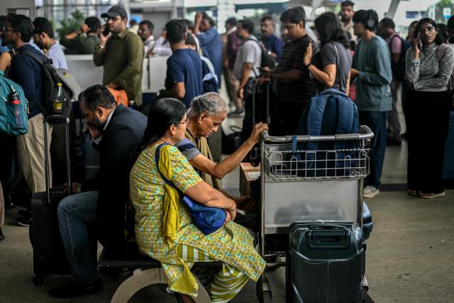 Passengers wait near the IndiGo Airlines kiosk at the Chennai International Airport in Chennai on December 5, 2025. Chaos gripped Indian airports on December 4 after the country's biggest airline IndiGo cancelled over 1,200 flights, stranding thousands of passengers. (Photo by R.Satish BABU / AFP)