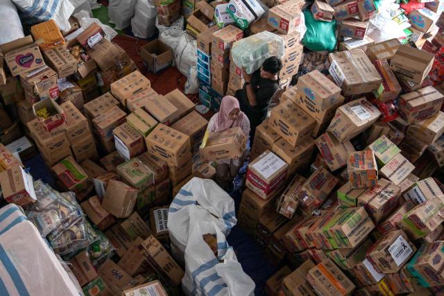 Volunteers pack supplies to be delivered to areas affected by flooding at a Regional Disaster Mitigation Agency in Sidoarjo, East Java province on December 5, 2025. Survivors in Indonesia were piecing back shattered lives December 5 after devastating floods killed more than 1,500 people across four countries, with fears of fresh misery as more rain looms. (Photo by JUNI KRISWANTO / AFP)