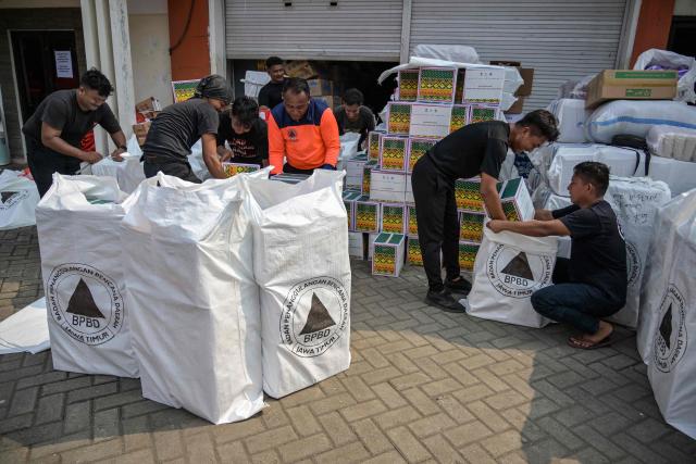 Volunteers pack supplies to be delivered to areas affected by flooding at a Regional Disaster Mitigation Agency in Sidoarjo, East Java province on December 5, 2025. Survivors in Indonesia were piecing back shattered lives December 5 after devastating floods killed more than 1,500 people across four countries, with fears of fresh misery as more rain looms. (Photo by JUNI KRISWANTO / AFP)