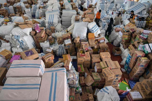 Volunteers pack supplies to be delivered to areas affected by flooding at a Regional Disaster Mitigation Agency in Sidoarjo, East Java province on December 5, 2025. Survivors in Indonesia were piecing back shattered lives December 5 after devastating floods killed more than 1,500 people across four countries, with fears of fresh misery as more rain looms. (Photo by JUNI KRISWANTO / AFP)