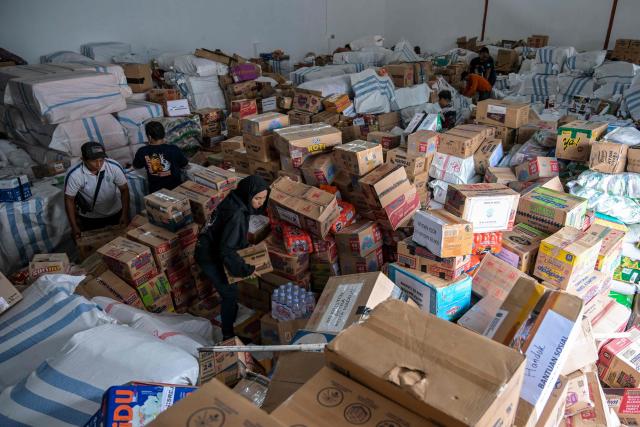 Volunteers pack supplies to be delivered to areas affected by flooding at a Regional Disaster Mitigation Agency in Sidoarjo, East Java province on December 5, 2025. Survivors in Indonesia were piecing back shattered lives December 5 after devastating floods killed more than 1,500 people across four countries, with fears of fresh misery as more rain looms. (Photo by JUNI KRISWANTO / AFP)