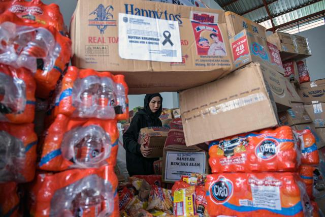 A volunteer packs supplies to be delivered to areas affected by flooding at a Regional Disaster Mitigation Agency in Sidoarjo, East Java province on December 5, 2025. Survivors in Indonesia were piecing back shattered lives December 5 after devastating floods killed more than 1,500 people across four countries, with fears of fresh misery as more rain looms. (Photo by JUNI KRISWANTO / AFP)