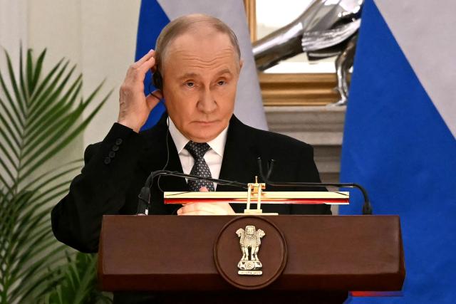 Russia's President Vladimir Putin adjusts his earpiece during joint press statements with India's Prime Minister Narendra Modi after their meeting at the Hyderabad House in New Delhi on December 5, 2025. (Photo by Sajjad HUSSAIN / AFP)