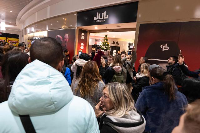 Customers wait at the entrance of the pop-up store of French rapper Jul on the day of its opening in Marseille, southern France on December 5, 2025. (Photo by Miguel MEDINA / AFP)