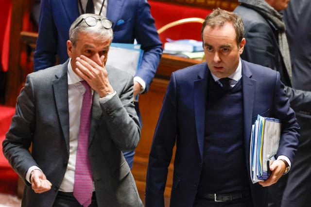 France's Prime Minister Sebastien Lecornu (R) and Les Democrates' MP Philippe Vigier (L) leave after MPs adopted the "revenue" section during a voting session focused on the 2026 social security budget bill (PLFSS) at the National Assembly, the French Parliament lower house, in Paris on December 5, 2025. (Photo by Ian LANGSDON / AFP)
