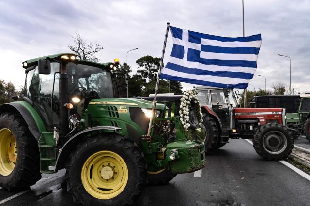 A Greece's national flag flies on a tractor as farmers block the road leading to the airport of Thessaloniki, with tractors during a protest over the reduced and delayed payment of European Union subsidies, on December 5, 2025. (Photo by Sakis Mitrolidis / AFP)
