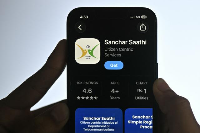 This photo illustration shows a man viewing the cyber safety application 'Sanchar Saathi' on a smartphone screen at an office in Bengaluru on December 5, 2025. India has ordered smartphone makers to pre-install a government-run cyber security app that cannot be removed, a move that has raised concerns about users' privacy. The country has a massive 1.16 billion mobile phone users, according to government data from 2024, and authorities say the app will better protect them from fraud. (Photo by Idrees MOHAMMED / AFP)
