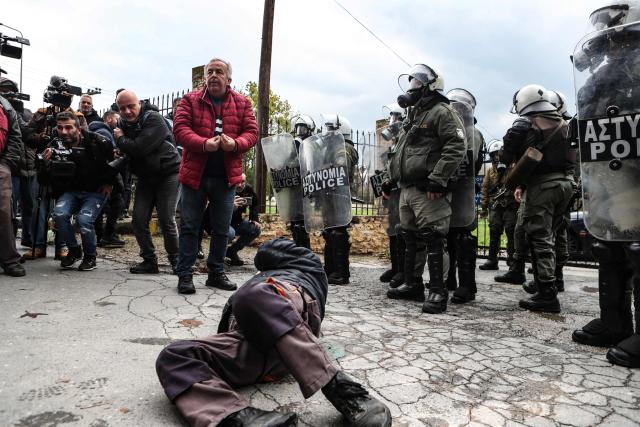 A protestor suffers from the smoke of the teargas fired by riot police as farmers block the road leading to the airport with their tractors during a protest over the reduced and delayed payment of European Union subsidies, in Thessaloniki on December 5, 2025. (Photo by AFP)