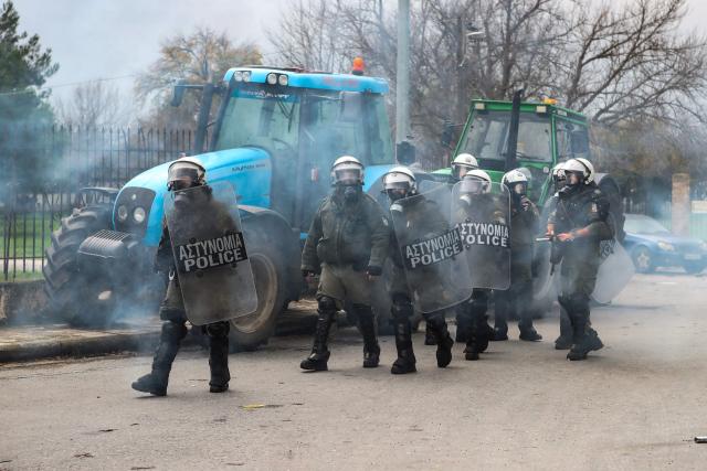 TOPSHOT - Riot police officers use tear gas to disperse farmers blocking the road leading to the airport with their tractors during a protest over the reduced and delayed payment of European Union subsidies, in Thessaloniki on December 5, 2025. (Photo by AFP)