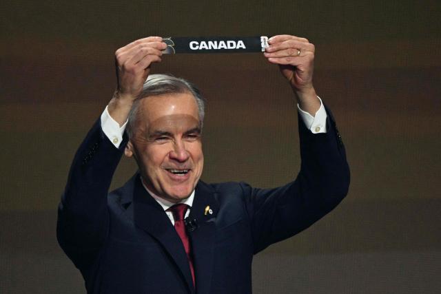 Canada's Prime Minister Mark Carney shows the card reading Canada during the draw for the 2026 FIFA Football World Cup taking place in the US, Canada and Mexico, at the Kennedy Center, in Washington, DC, on December 5, 2025. (Photo by Jim WATSON / AFP)