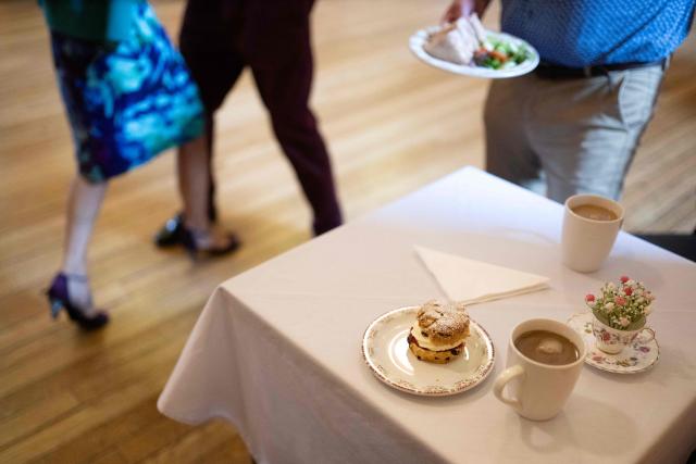 Tea, scones and sandwiches are served as ballroom dancers take part in an afternoon Tea Dance in the Riley-Smith Hall, in Tadcaster, northern England on October 15, 2025. Tea dances, which evolved from the tradition of afternoon tea in the late 19th century, are enjoying a revival, especially since the pandemic. Often cited as an effective way to combat loneliness, the dances are also attributed to improving the participants' mental and physical health. Frequently hosted in Victorian and Edwardian-era halls, tea dances typically offer a mixture of ballroom and sequence dancing styles and feature refreshments of tea, coffee and cakes. (Photo by Oli SCARFF / AFP)