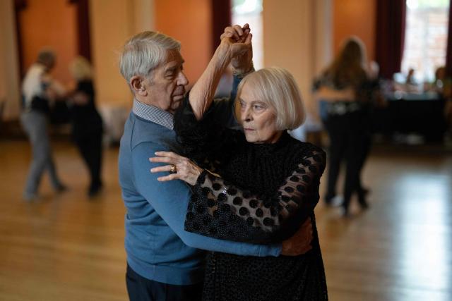 Ballroom dancers take part in an afternoon Tea Dance in the Riley-Smith Hall, in Tadcaster, northern England on October 15, 2025. Tea dances, which evolved from the tradition of afternoon tea in the late 19th century, are enjoying a revival, especially since the pandemic. Often cited as an effective way to combat loneliness, the dances are also attributed to improving the participants' mental and physical health. Frequently hosted in Victorian and Edwardian-era halls, tea dances typically offer a mixture of ballroom and sequence dancing styles and feature refreshments of tea, coffee and cakes. (Photo by Oli SCARFF / AFP)