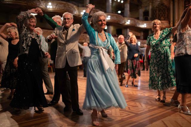Ballroom dancers take part in a Tea Dance, accompanied by a live organist, in the Blackpool Tower Ballroom, in Blackpool, north west England on October 22, 2025. Tea dances, which evolved from the tradition of afternoon tea in the late 19th century, are enjoying a revival, especially since the pandemic. Often cited as an effective way to combat loneliness, the dances are also attributed to improving the participants' mental and physical health. Frequently hosted in Victorian and Edwardian-era halls, tea dances typically offer a mixture of ballroom and sequence dancing styles and feature refreshments of tea, coffee and cakes. (Photo by Oli SCARFF / AFP)