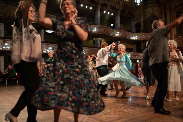 Ballroom dancers take part in a Tea Dance, accompanied by a live organist, in the Blackpool Tower Ballroom, in Blackpool, north west England on October 22, 2025. Tea dances, which evolved from the tradition of afternoon tea in the late 19th century, are enjoying a revival, especially since the pandemic. Often cited as an effective way to combat loneliness, the dances are also attributed to improving the participants' mental and physical health. Frequently hosted in Victorian and Edwardian-era halls, tea dances typically offer a mixture of ballroom and sequence dancing styles and feature refreshments of tea, coffee and cakes. (Photo by Oli SCARFF / AFP)