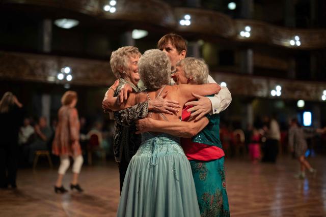 Ballroom dancers embrace at the end of a dance during an afternoon Tea Dance, accompanied by a live organist, in the Blackpool Tower Ballroom, in Blackpool, north west England on October 22, 2025. Tea dances, which evolved from the tradition of afternoon tea in the late 19th century, are enjoying a revival, especially since the pandemic. Often cited as an effective way to combat loneliness, the dances are also attributed to improving the participants' mental and physical health. Frequently hosted in Victorian and Edwardian-era halls, tea dances typically offer a mixture of ballroom and sequence dancing styles and feature refreshments of tea, coffee and cakes. (Photo by Oli SCARFF / AFP)