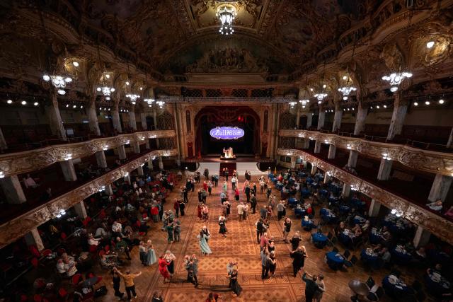 Ballroom dancers take part in a Tea Dance, accompanied by a live organist, in the Blackpool Tower Ballroom, in Blackpool, north west England on October 22, 2025. Tea dances, which evolved from the tradition of afternoon tea in the late 19th century, are enjoying a revival, especially since the pandemic. Often cited as an effective way to combat loneliness, the dances are also attributed to improving the participants' mental and physical health. Frequently hosted in Victorian and Edwardian-era halls, tea dances typically offer a mixture of ballroom and sequence dancing styles and feature refreshments of tea, coffee and cakes. (Photo by Oli SCARFF / AFP)