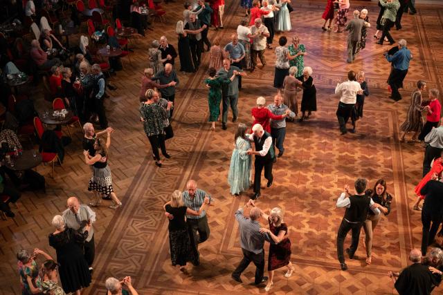 TOPSHOT - Ballroom dancers take part in a Tea Dance, accompanied by a live organist, in the Blackpool Tower Ballroom, in Blackpool, north west England on October 22, 2025. Tea dances, which evolved from the tradition of afternoon tea in the late 19th century, are enjoying a revival, especially since the pandemic. Often cited as an effective way to combat loneliness, the dances are also attributed to improving the participants' mental and physical health. Frequently hosted in Victorian and Edwardian-era halls, tea dances typically offer a mixture of ballroom and sequence dancing styles and feature refreshments of tea, coffee and cakes. (Photo by Oli SCARFF / AFP)