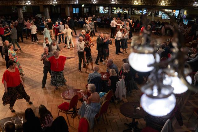 Ballroom dancers take part in a Tea Dance, accompanied by a live organist, in the Blackpool Tower Ballroom, in Blackpool, north west England on October 22, 2025. Tea dances, which evolved from the tradition of afternoon tea in the late 19th century, are enjoying a revival, especially since the pandemic. Often cited as an effective way to combat loneliness, the dances are also attributed to improving the participants' mental and physical health. Frequently hosted in Victorian and Edwardian-era halls, tea dances typically offer a mixture of ballroom and sequence dancing styles and feature refreshments of tea, coffee and cakes. (Photo by Oli SCARFF / AFP)