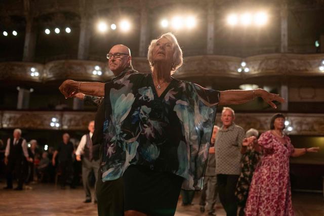Ballroom dancers take part in a Tea Dance, accompanied by a live organist, in the Blackpool Tower Ballroom, in Blackpool, north west England on October 22, 2025. Tea dances, which evolved from the tradition of afternoon tea in the late 19th century, are enjoying a revival, especially since the pandemic. Often cited as an effective way to combat loneliness, the dances are also attributed to improving the participants' mental and physical health. Frequently hosted in Victorian and Edwardian-era halls, tea dances typically offer a mixture of ballroom and sequence dancing styles and feature refreshments of tea, coffee and cakes. (Photo by Oli SCARFF / AFP)