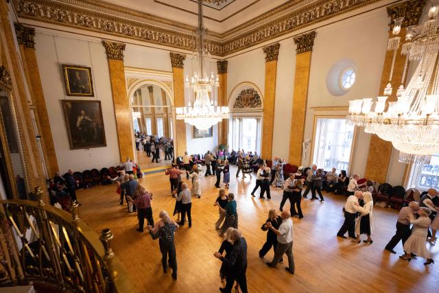 Ballroom dancers take part in a Tea Dance, in the Main Ballroom of Liverpool Town Hall, in Liverpool, north west England on November 17, 2025. Tea dances, which evolved from the tradition of afternoon tea in the late 19th century, are enjoying a revival, especially since the pandemic. Often cited as an effective way to combat loneliness, the dances are also attributed to improving the participants' mental and physical health. Frequently hosted in Victorian and Edwardian-era halls, tea dances typically offer a mixture of ballroom and sequence dancing styles and feature refreshments of tea, coffee and cakes. (Photo by Oli SCARFF / AFP)