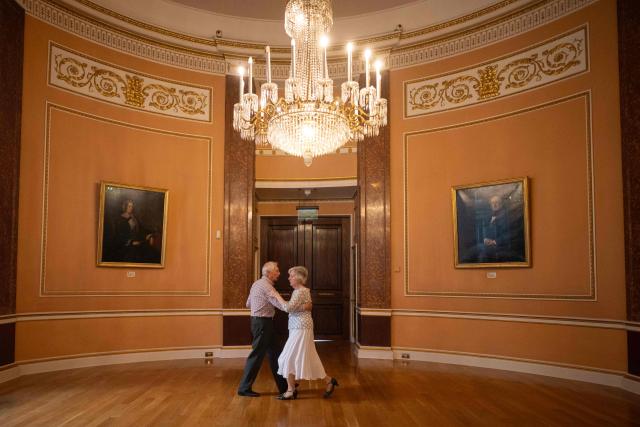 TOPSHOT - A ballroom dancing couple practice their moves in a side room during a Tea Dance, held in the Main Ballroom of Liverpool Town Hall, in Liverpool, north west England on November 17, 2025. Tea dances, which evolved from the tradition of afternoon tea in the late 19th century, are enjoying a revival, especially since the pandemic. Often cited as an effective way to combat loneliness, the dances are also attributed to improving the participants' mental and physical health. Frequently hosted in Victorian and Edwardian-era halls, tea dances typically offer a mixture of ballroom and sequence dancing styles and feature refreshments of tea, coffee and cakes. (Photo by Oli SCARFF / AFP)