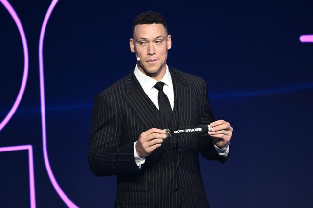 US Draw assistant Aaron Judge shows the card reading Cote D'Ivore during the draw for the 2026 FIFA Football World Cup taking place in the US, Canada and Mexico, at the Kennedy Center, in Washington, DC, on December 5, 2025. (Photo by Brendan SMIALOWSKI / AFP)