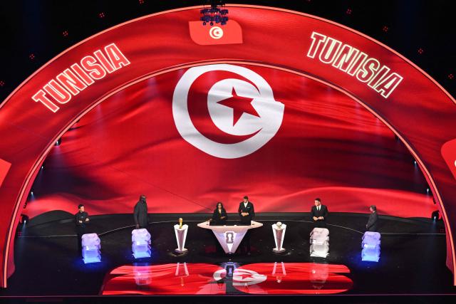 Tunisia's flag is displayed on a screen during the draw for the 2026 FIFA Football World Cup taking place in the US, Canada and Mexico, at the Kennedy Center, in Washington, DC, on December 5, 2025. (Photo by Roberto SCHMIDT / AFP)