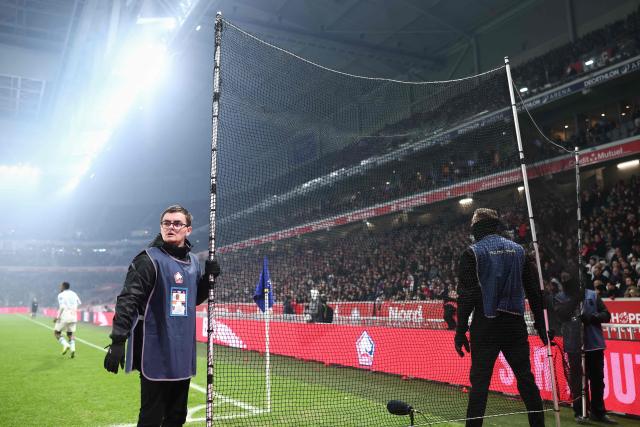 Security guards hold a protection net as Lille's supporters throw paper wads during the French L1 football match between Lille LOSC and Olympique de Marseille (OM) at the Pierre-Mauroy stadium in Villeneuve-d'Ascq, northern France, on December 5, 2025. (Photo by Sameer Al-Doumy / AFP)