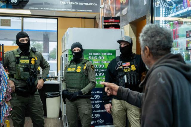 US Customs and Border Patrol agents listen to a man as they stop at the convenience store of a gas station while participating in an immigration raid in Kenner, Louisiana, on December 5, 2025. The US Department of Homeland Security announced on December 3 it has launched a federal immigration enforcement operation, named "Operation Catahoula Crunch," in the New Orleans, Louisiana, area. (Photo by Adam GRAY / AFP)