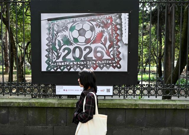A woman walks past 2026 FIFA world cup themed watercolor paintings by Cynthia Saide at Chapultepec Park in Mexico City on December 5, 2025. The draw for the 2026 World Cup, held this Friday in Washington, shaped an unprecedented group stage: 48 teams distributed into 12 groups of four teams each, with the hosts United States, Mexico and Canada seeded in Groups D, A and B, respectively. (Photo by Yuri CORTEZ / AFP)