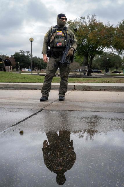 A US Customs and Border Patrol agent stands guard as Commander Gregory Bovino conducts interviews with residents during operations at a park in Metairie, Louisiana, on December 5, 2025. The US Department of Homeland Security announced on December 3 it has launched a federal immigration enforcement operation, named "Operation Catahoula Crunch," in the New Orleans, Louisiana, area. (Photo by Adam GRAY / AFP)