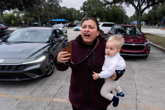 A woman holding her baby reacts as US Customs and Border Patrol agents interview people at a park in Metairie, Louisiana, on December 5, 2025. The US Department of Homeland Security announced on December 3 it has launched a federal immigration enforcement operation, named "Operation Catahoula Crunch," in the New Orleans, Louisiana, area. (Photo by Adam GRAY / AFP)