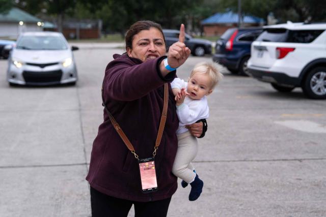 A woman holding her baby reacts as US Customs and Border Patrol agents interview people at a park in Metairie, Louisiana, on December 5, 2025. The US Department of Homeland Security announced on December 3 it has launched a federal immigration enforcement operation, named "Operation Catahoula Crunch," in the New Orleans, Louisiana, area. (Photo by Adam GRAY / AFP)