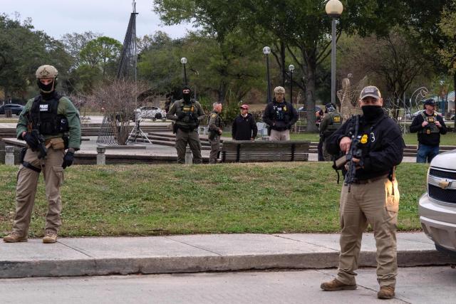 Guarded by fellow agents, US Customs and Border Patrol Commander Gregory Bovino (C-L) interviews resident Julio Rosas during an immigration raid at a park in Metairie, Louisiana, on December 5, 2025. The US Department of Homeland Security announced on December 3 it has launched a federal immigration enforcement operation, named "Operation Catahoula Crunch," in the New Orleans, Louisiana, area. (Photo by Adam GRAY / AFP)