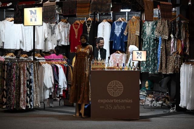 A man waits for customers at Expoartesanias Fair, which highlights artisans work and their ancestral creations in Bogota on December 5, 2025. (Photo by Raul ARBOLEDA / AFP)