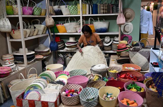 A man waits for customers at Expoartesanias Fair, which highlights artisans work and their ancestral creations in Bogota on December 5, 2025. (Photo by Raul ARBOLEDA / AFP)