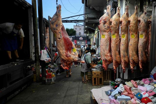 A worker unloads sides of beef from a truck at Mataderos neighborhood in Buenos Aires, on December 5, 2025. (Photo by Luis ROBAYO / AFP)