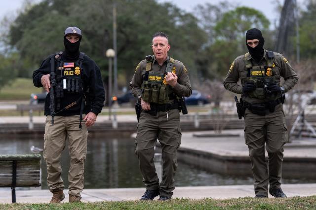 US Customs and Border Patrol Commander Gregory Bovino (C), flanked by fellow agents, leaves a park after interviewing residents during operations at a park in Metairie, Louisiana, on December 5, 2025. The US Department of Homeland Security announced on December 3 it has launched a federal immigration enforcement operation, named "Operation Catahoula Crunch," in the New Orleans, Louisiana, area. (Photo by Adam GRAY / AFP)