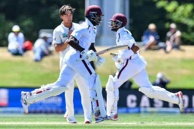 New Zealand's Zak Foulkes (L) looks on as West Indies' Justin Greaves and Shai Hope (R) run between the wickets on day five of the first Test cricket match between New Zealand and West Indies at Hagley Oval in Christchurch on December 6, 2025. (Photo by Sanka Vidanagama / AFP)