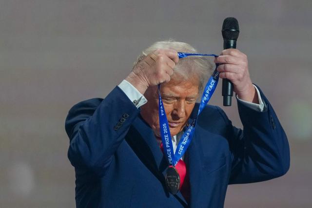 US President Donald Trump puts on a medal as he receives the FIFA Peace Prize from FIFA President Gianni Infantino during the draw for the 2026 FIFA Football World Cup taking place in the US, Canada and Mexico, at the Kennedy Center, in Washington, DC, on December 5, 2025. (Photo by Stephanie Scarbrough / POOL / AFP)