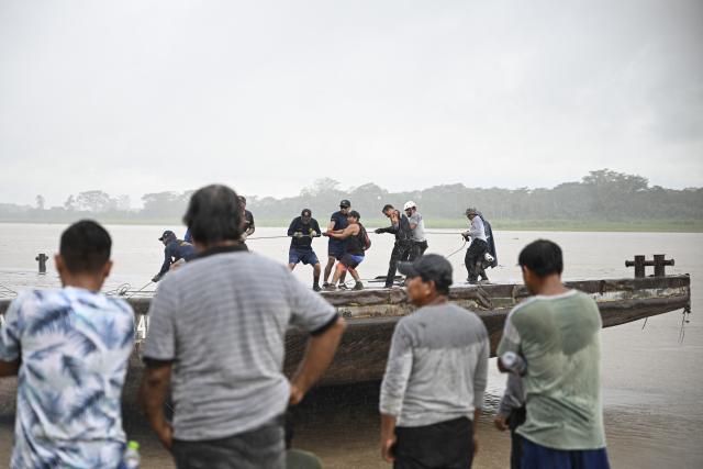 Police officers and members of the community work on the area of a vessel accident at the port of Iparia, in the Ucayali department in Peru's central jungle, on December 5, 2025. At least 12 people, including three children, died on December 1, 2025, when a landslide buried two boats docked at a river port in central Peru, with dozens of others missing, officials said. (Photo by Hugo Alejos / AFP)