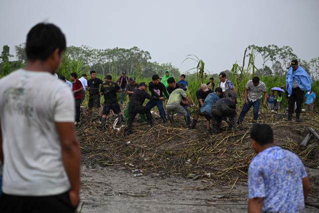 Police officers and members of the community work on the area of a vessel accident at the port of Iparia, in the Ucayali department in Peru's central jungle, on December 5, 2025. At least 12 people, including three children, died on December 1, 2025, when a landslide buried two boats docked at a river port in central Peru, with dozens of others missing, officials said. (Photo by Hugo Alejos / AFP)