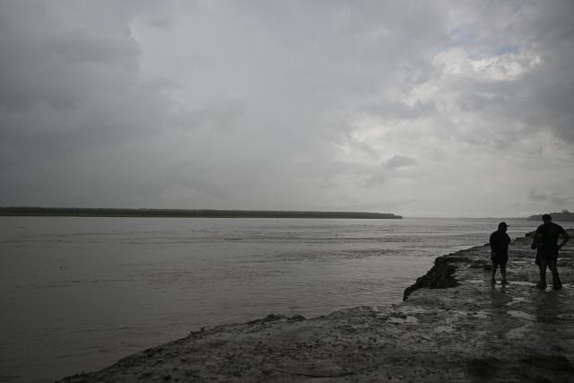 Police officers and members of the community work on the area of a vessel accident at the port of Iparia, in the Ucayali department in Peru's central jungle, on December 5, 2025. At least 12 people, including three children, died on December 1, 2025, when a landslide buried two boats docked at a river port in central Peru, with dozens of others missing, officials said. (Photo by Hugo Alejos / AFP)
