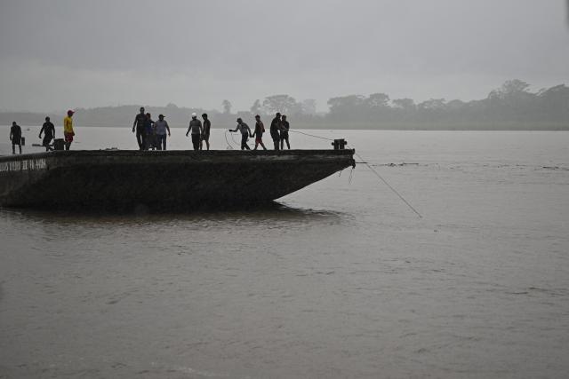 Police officers and members of the community work on the area of a vessel accident at the port of Iparia, in the Ucayali department in Peru's central jungle, on December 5, 2025. At least 12 people, including three children, died on December 1, 2025, when a landslide buried two boats docked at a river port in central Peru, with dozens of others missing, officials said. (Photo by Hugo Alejos / AFP)