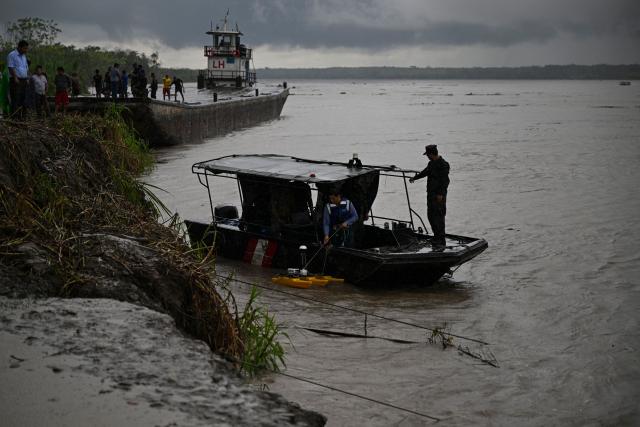 Police officers and members of the community work on the area of a vessel accident at the port of Iparia, in the Ucayali department in Peru's central jungle, on December 5, 2025. At least 12 people, including three children, died on December 1, 2025, when a landslide buried two boats docked at a river port in central Peru, with dozens of others missing, officials said. (Photo by Hugo Alejos / AFP)
