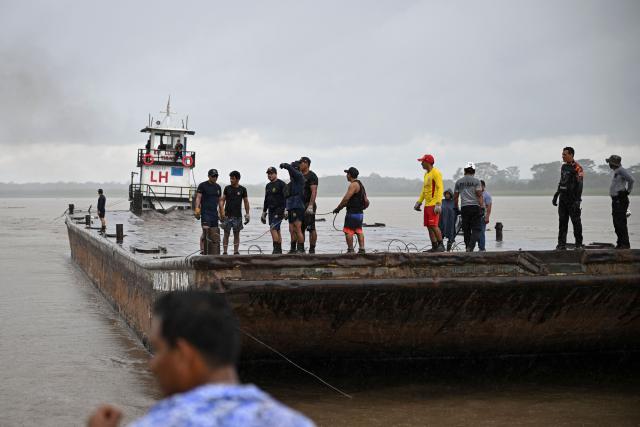 Police officers and members of the community work on the area of a vessel accident at the port of Iparia, in the Ucayali department in Peru's central jungle, on December 5, 2025. At least 12 people, including three children, died on December 1, 2025, when a landslide buried two boats docked at a river port in central Peru, with dozens of others missing, officials said. (Photo by Hugo Alejos / AFP)