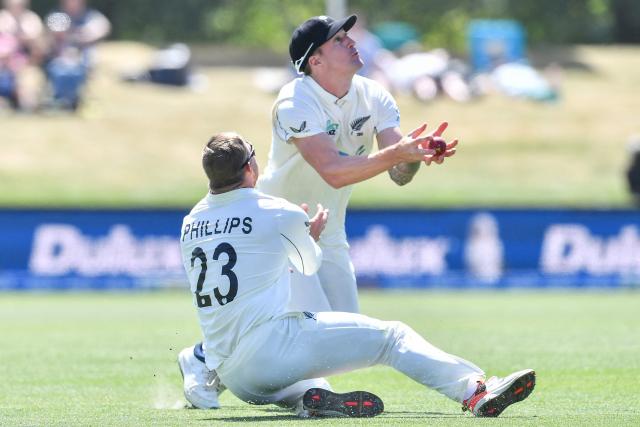 New Zealand's Blair Tickner (R) drops a catch off West Indies' Kemar Roach next to Glenn Phillip during day five of the first Test cricket match between New Zealand and West Indies at Hagley Oval in Christchurch on December 6, 2025. (Photo by Sanka Vidanagama / AFP)