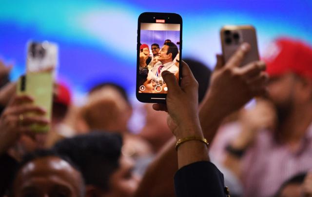 A supporter takes pictures with his mobile phone of Salvador Nasralla, presidential candidate for the opposition Liberal Party, in Tegucigalpa on December 5, 2025. Hondurans waited on December 5, 2025, for results from a tight presidential race held five days earlier, with a technical tie persisting between Asfura, a right-wing candidate favored by US President Donald Trump, and the candidate for the Liberal Party Nasralla. (Photo by Orlando SIERRA / AFP)