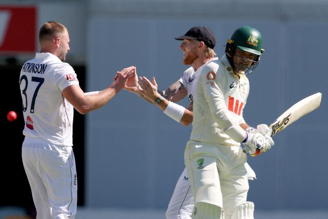 England’s captain Ben Stokes (C) celebrates with Gus Atkinson (L) after he dismissed Australia’s Alex Carey (R) on day three of the second Ashes cricket Test match between Australia and England at The Gabba in Brisbane on December 6, 2025. (Photo by DAVID GRAY / AFP)